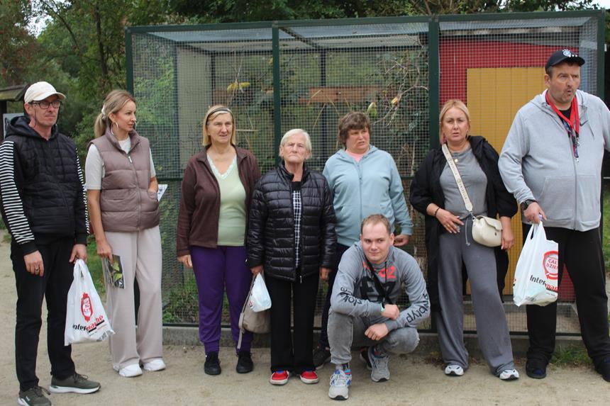 Uczestnicy oraz kadra stojący na tle klatki ze zwierzętami D