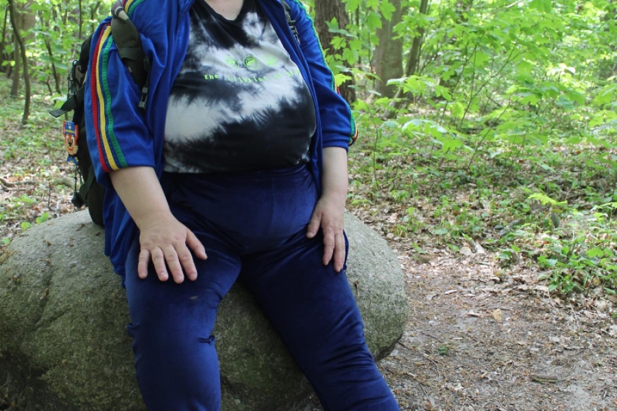 Uczestniczka siedząca na kamieniu pozuje do zdjęcia.