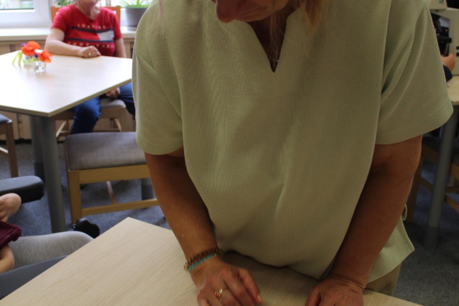 Uczestniczka obserwująca próbki bakterii na tle grupy. 