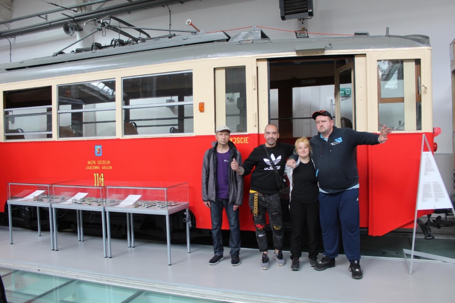 Uczestnicy pozujący do zdjęcia na tle tramwaju.