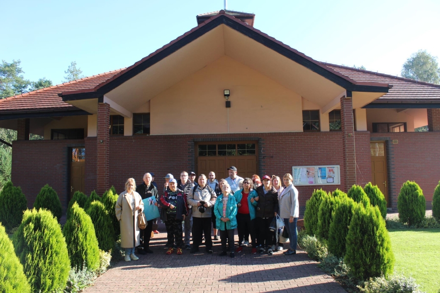 1. Uczestnicy wraz z terapeutami i Księdzem pozują do zdjęcia grupowego na tle Kościoła.