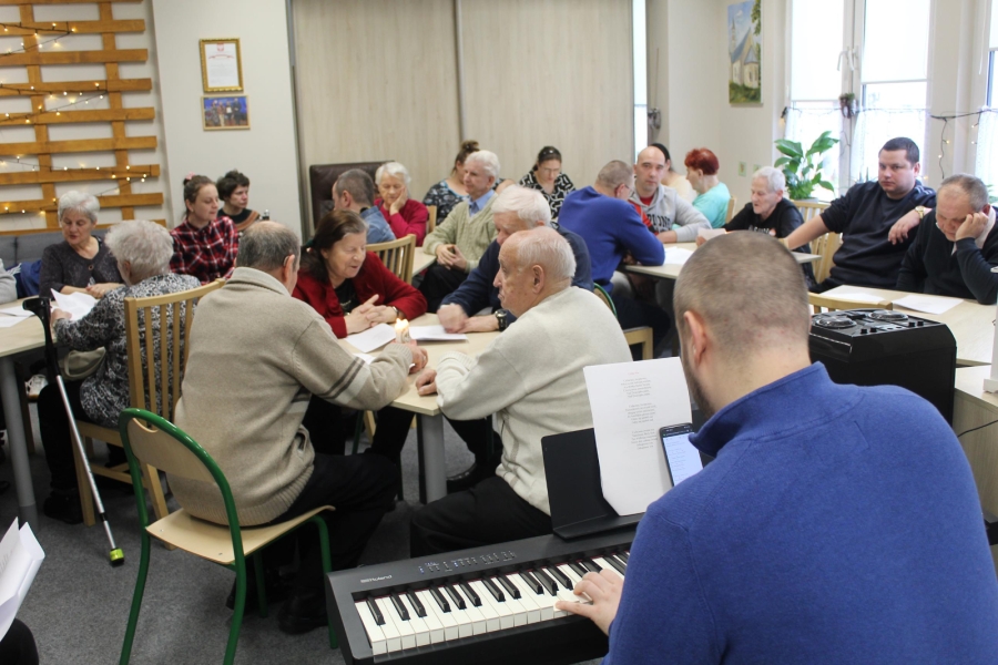2.Terapeuta grający na pianinie na tle śpiewających osób