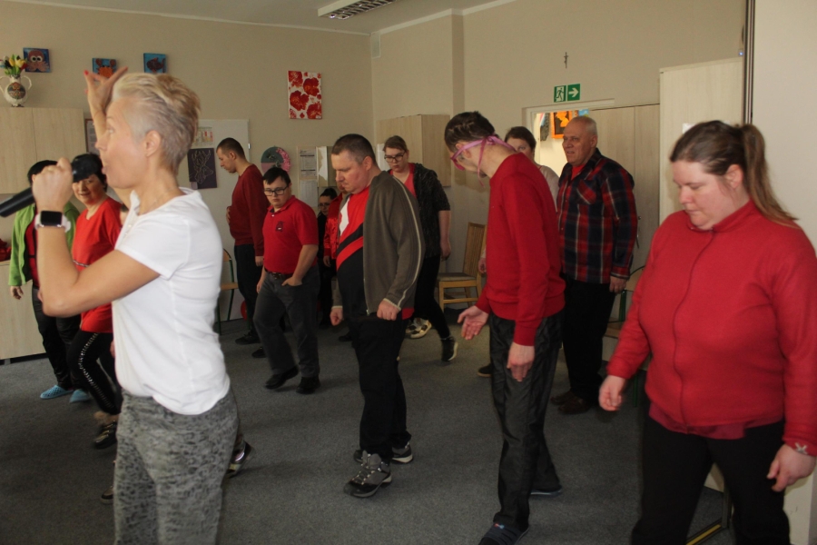 6.Instruktorka tańca wykonująca ruchy taneczne na tle grupy powtarzającej ruchy 