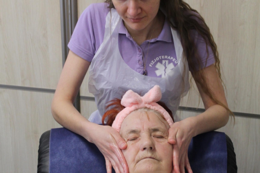 2.Fizjoterapeutka masująca twarz uczestniczki siedzącej na fotelu