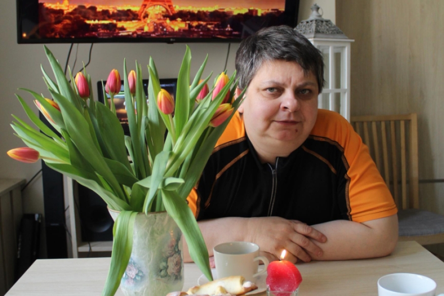 3.Uczestniczka siedząca przy stole na tle wazonu z tulipanami