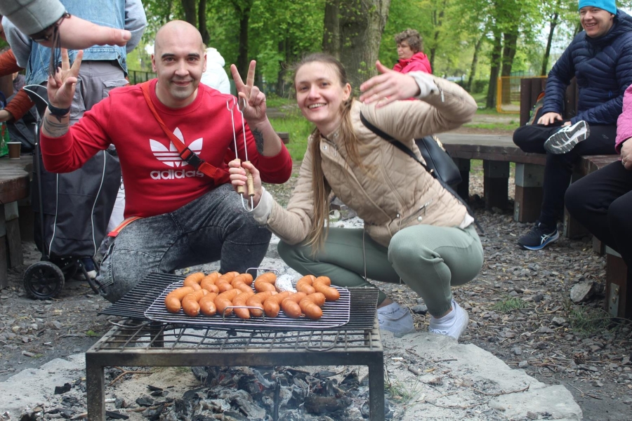 1.Fizjoterapeutka oraz uczestnik pozują do zdjęcia przed kiełbaskami na grillu