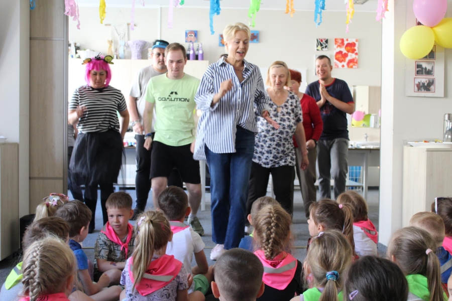 4.Instruktorka tańca oraz uczestnicy wykonujący taniec na tle widowni