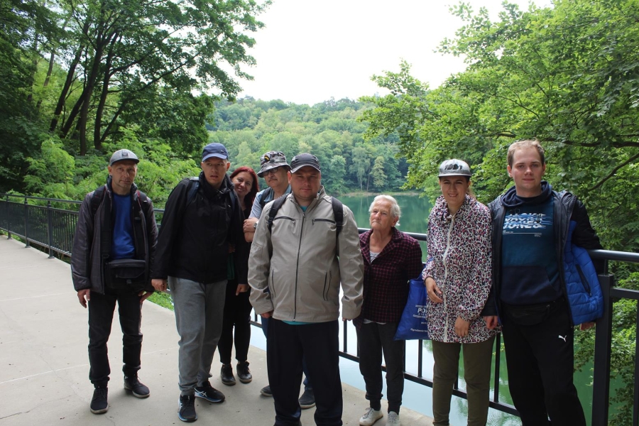 4.Uczestnicy i terapeuta na mostku stojący na tle jeziora oraz drzew