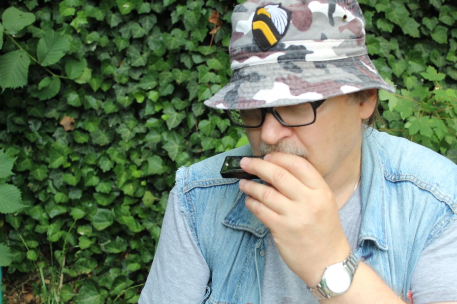 6.Uczestnik w kapeluszu moro grający na harmonicje ustnej