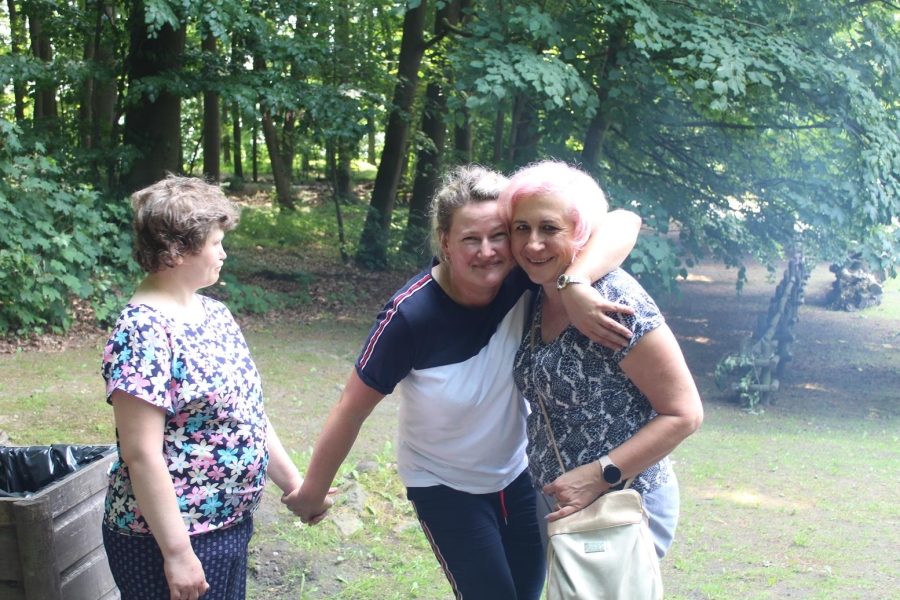 6.Uczestniczka oraz terapeutka przutulająca mamę uczestniczki na tle drzew