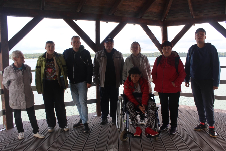 6.Grupa uczestników na drewnianej kładce na tle jeziora Morzycko