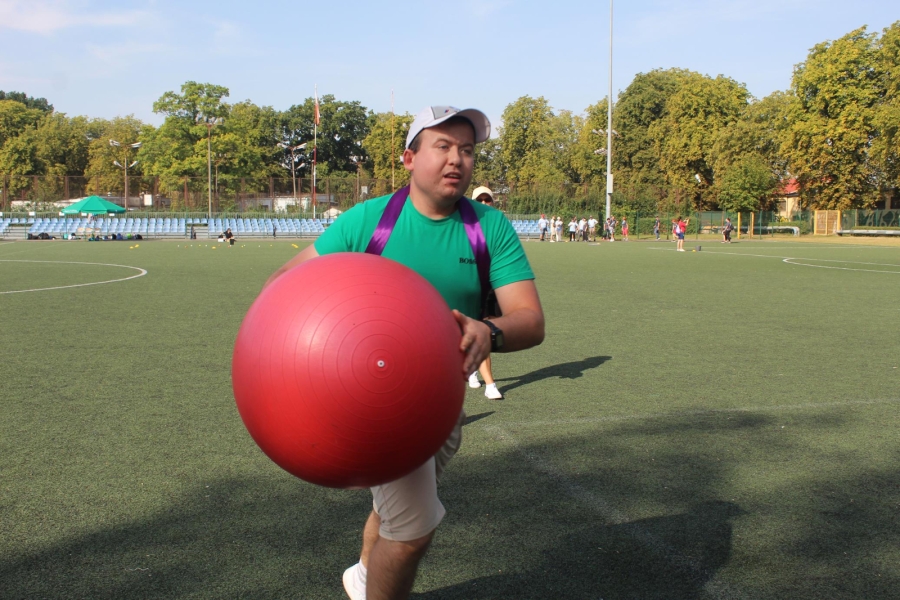 19.Uczestnik biegnący z dużą czerwoną piłką po boisku