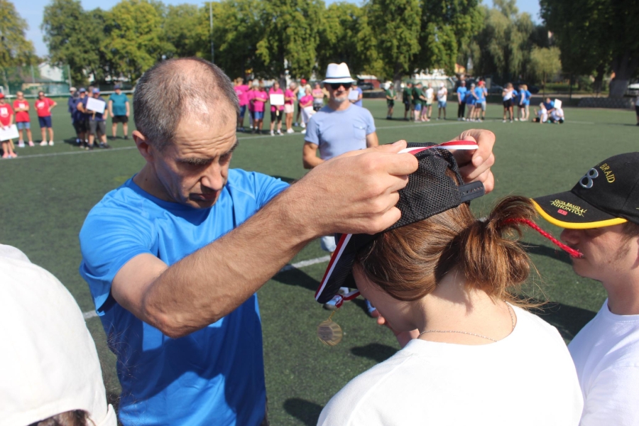 4.Uczestnik zawieszający medal na szyi uczestniczki na tle innych drużyn