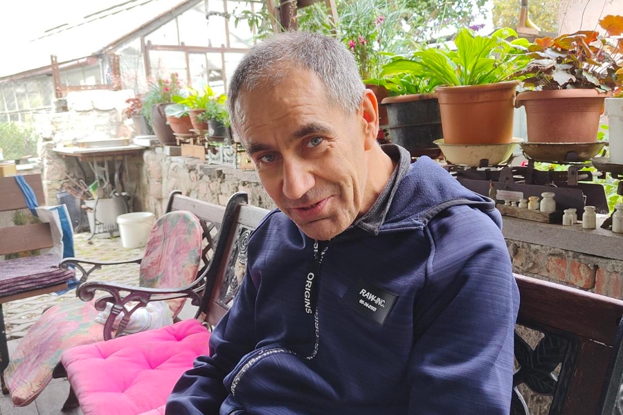 4.Uczestnik siedzący na ławce na tle kwiatów