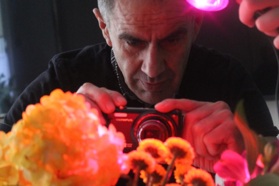 1.Uczestnik za oświetlonymi kwiatami trzymający aparat