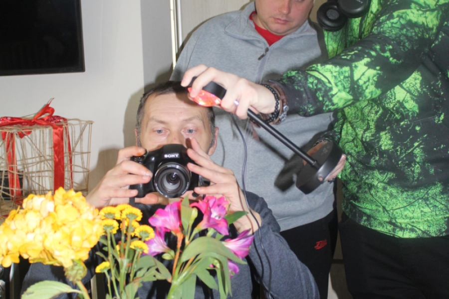 2.Uczestnicy oraz instruktor wykonujący zdjęcia kwiatom w wazonie