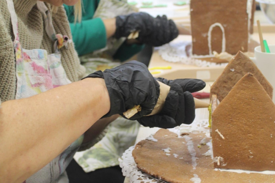 6.Uczestniczka ozdabiająca domek z piernika na tle pozostałych uczestników