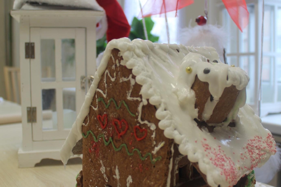 8.Domek z piernika z białym dachem, zdobionymi oknami oraz kominem