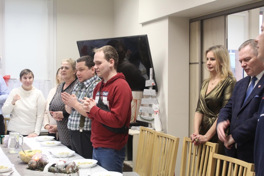 2.Stojący uczestnicy, kadra oraz zaproszeni goście przy stole wigilijnym ze złożonymi dłońmi do modlitwy