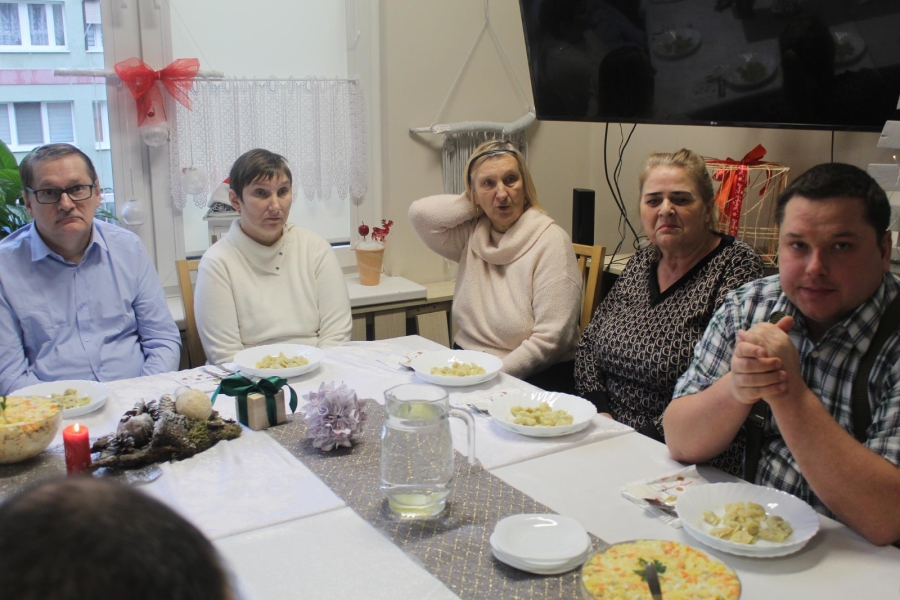 6.)Uczestnicy przy stole wigilijnym na tle wigilijnych potraw.