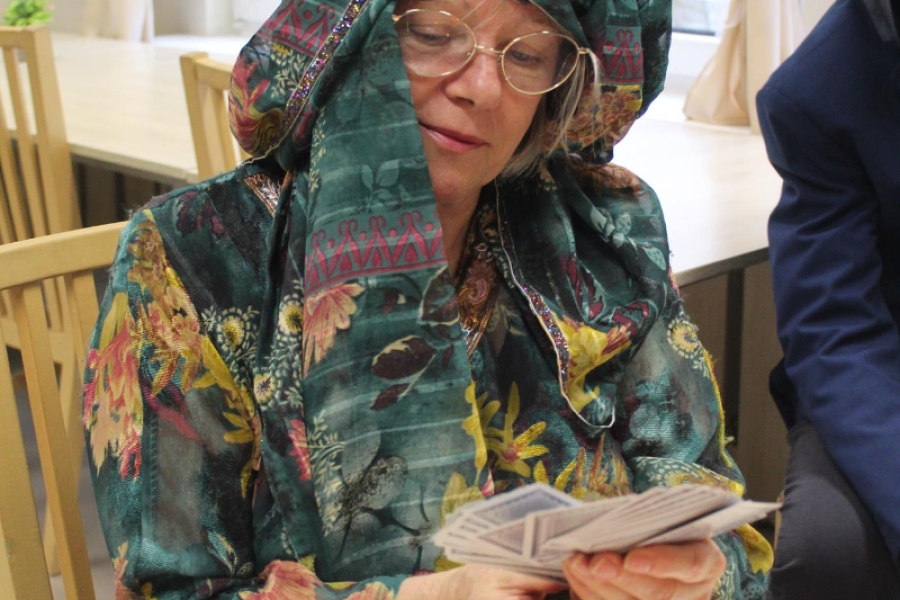 2.Uczestniczka w kolorowej chuście patrząca w karty