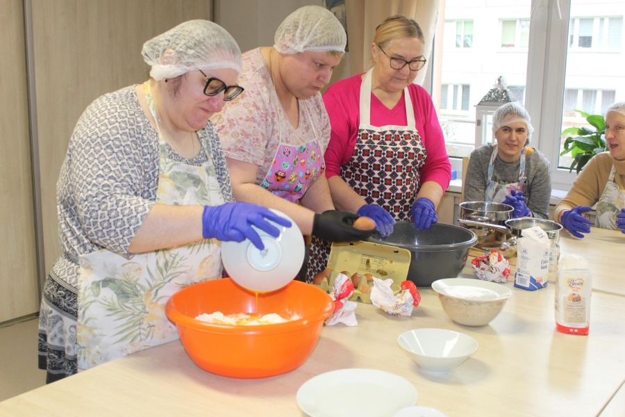 3.Uczestnicy oraz mama uczestnika wyrabiający ciasto na pączki przy stole