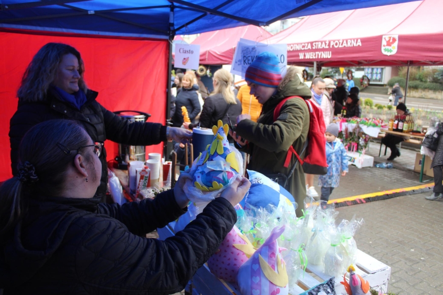 2.Uczestnicy oraz terapeutka podający ozdoby wielkanocne 