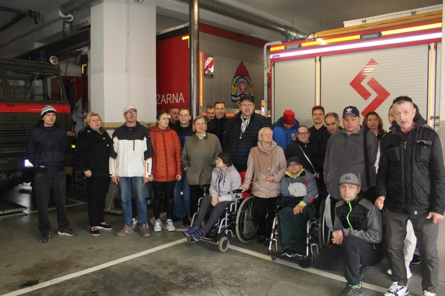 1.Grupa uczestników oraz strażaków stojąca na tle wozów strażackich