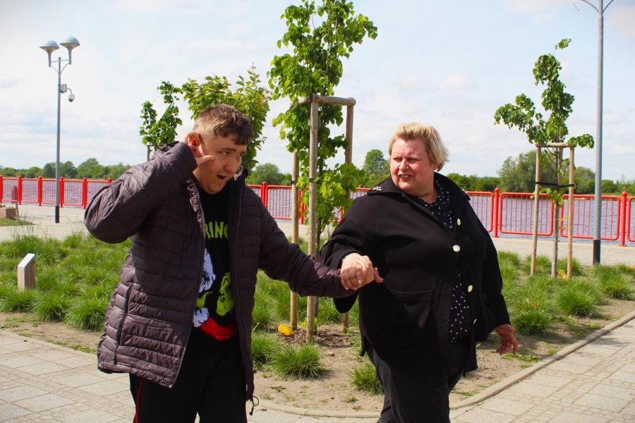 7.Uczestnik oraz opiekun spacerujący na tle zieleni