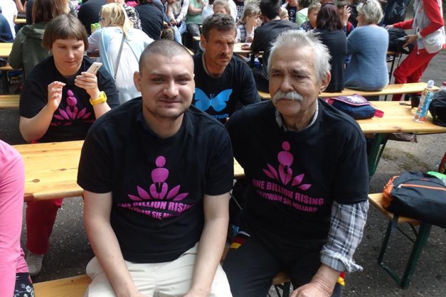 Uczestnicy odpoczywający na ławce na tle gości