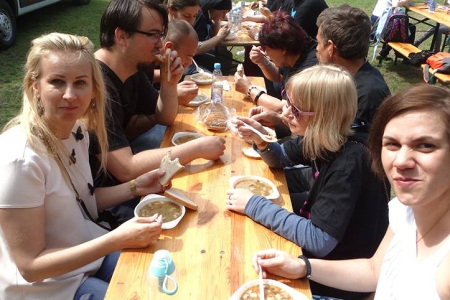 Uczestnicy wraz z terapeutami podczas posiłku przy drewnianym stole