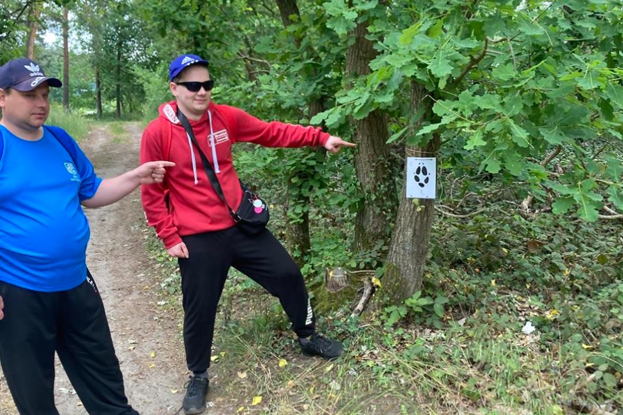 7.Uczestnicy wskazujący palcami na kartkę z zagadką w lesie