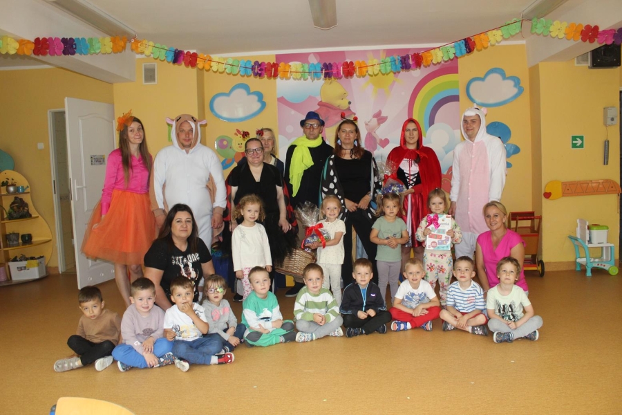 3.Uczestnicy oraz kadra ŚDS w Gryfinie w kolorowych strojach oraz dzieci z przedszkola na tle ściany z tęczą