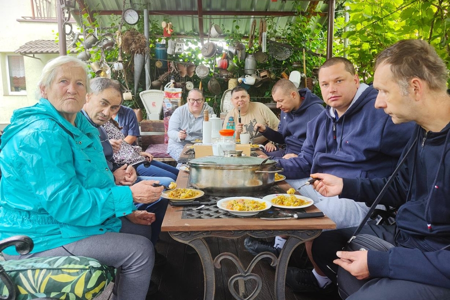 2.Uczestnicy przy stole w altanie jedzący obiad