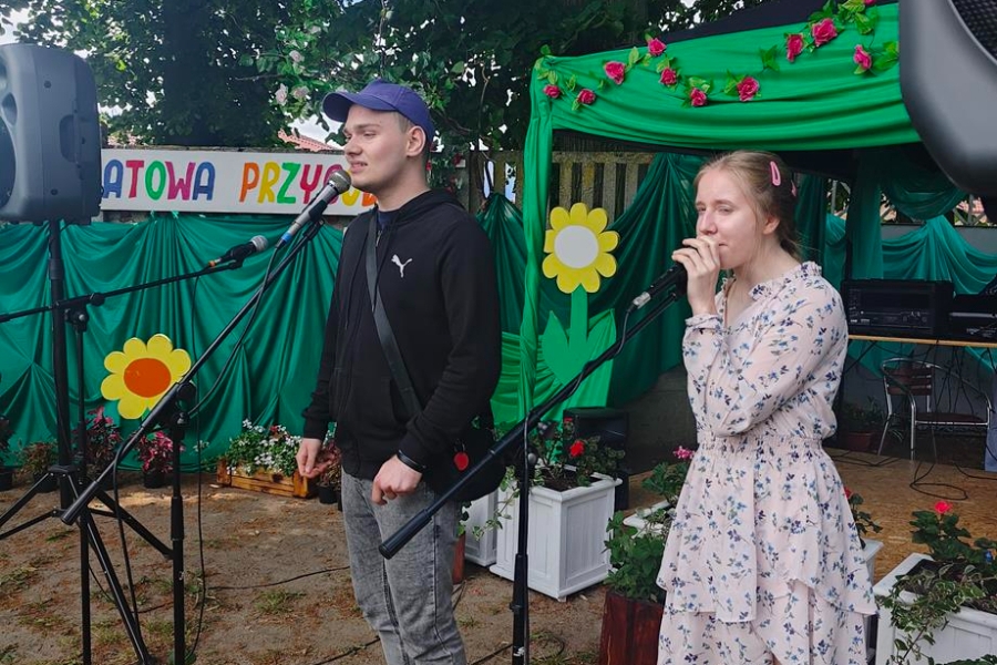 3.Uczestnik ŚDS w Gryfinie z koleżanką śpiewający przy mikrofonach na tle materiałowych słoneczni