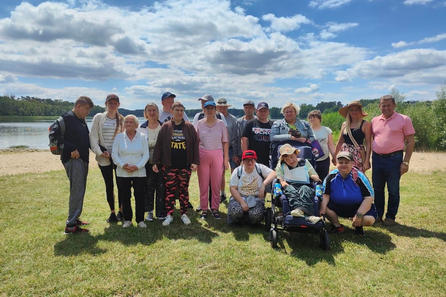 1.Grupa uczestników oraz terapeutów na tle jeziora oraz błękinego nieba