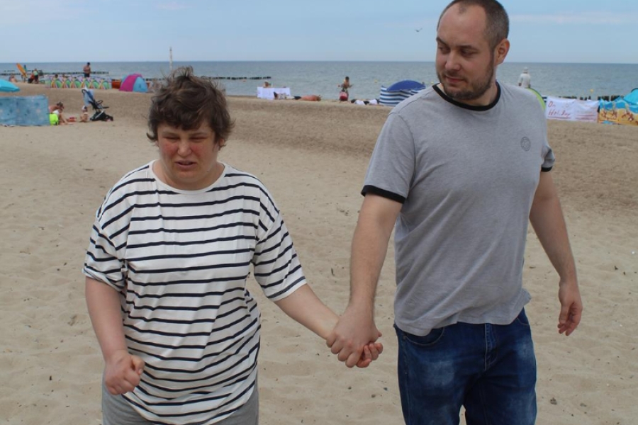 6.Uczestniczka oraz terapeuta spacerujący po plaży na tle morza