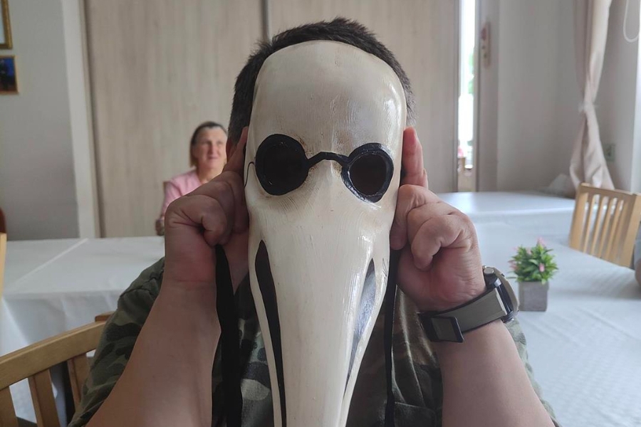 2.Uczestniczka przykładająca do twarzy dużą białą maskę z dziobem ptaka