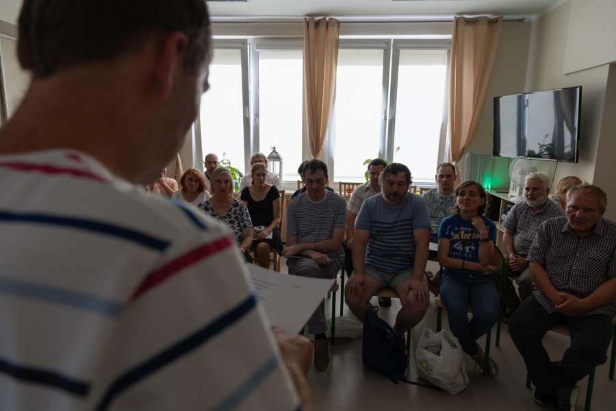 2.Poeta recytujący wiersze na tle publiki siedzącej na krzesłach