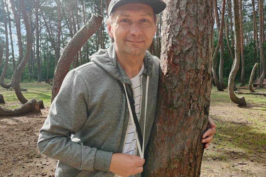 3.Uśmiechający się uczestnik przytulający drzewo