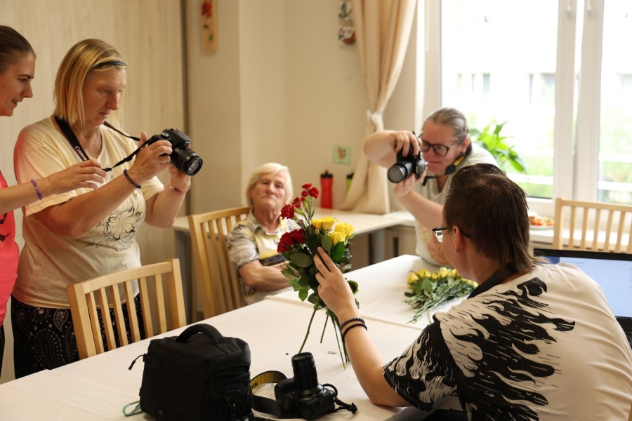 1.Uczestnicy wykonujący zdjęcie czerwonych kwiatów trzymanych przez pana Andrzeja