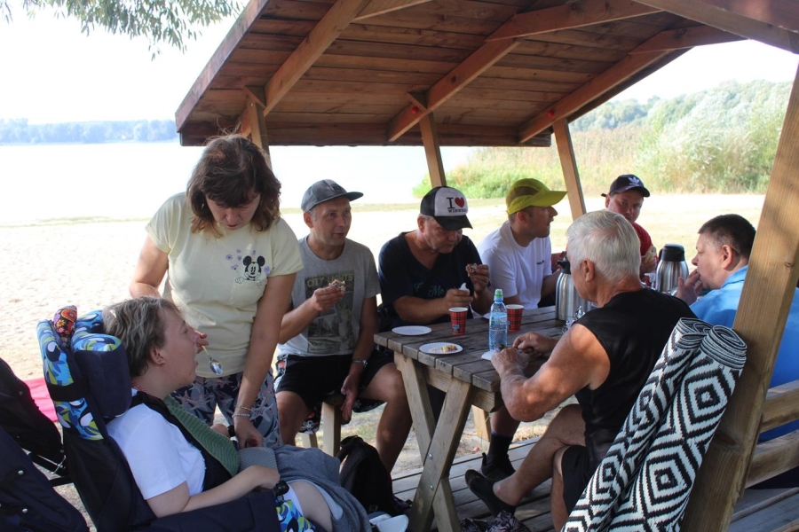 1.Uczestnicy pod drewnianą altaną jedzący ciasto 