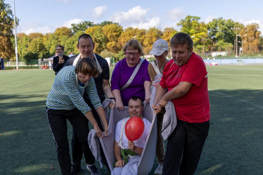 5.Uczestnik z czerwonym balonem przenoszony w kocu podczas konkurencji 