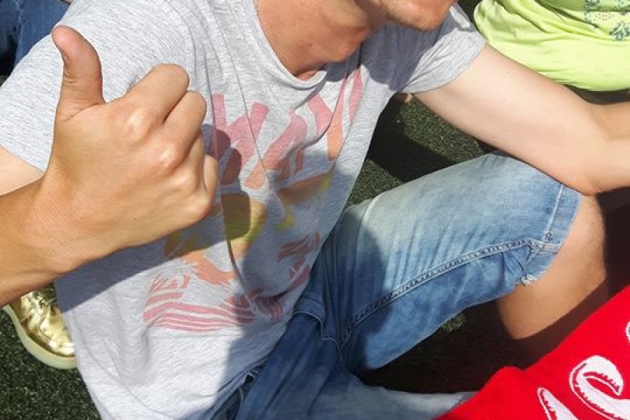 Uczestnik z namalowaną flagą Polski na policzku, trzymający szalik