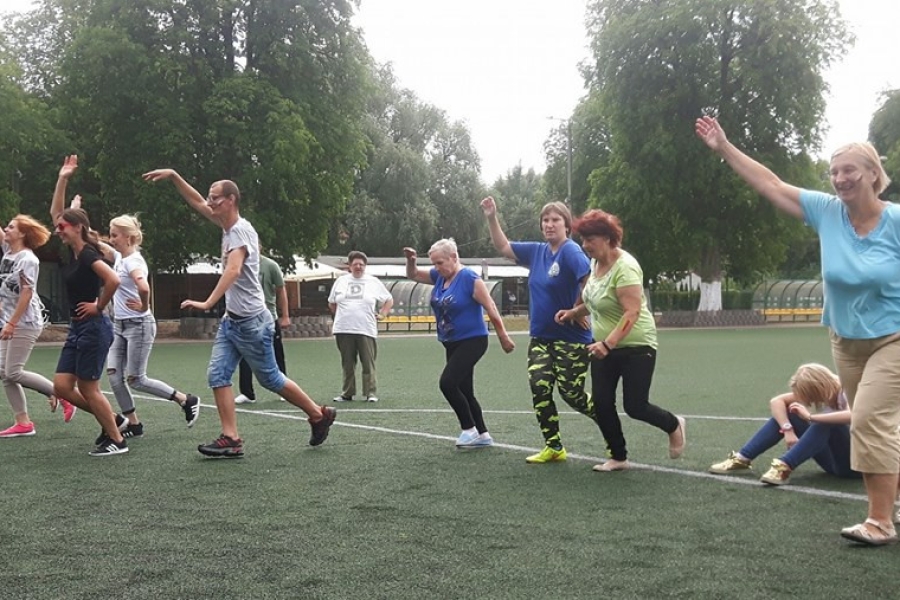 Uczestnicy wykonujący rozgrzewkę na boisku 