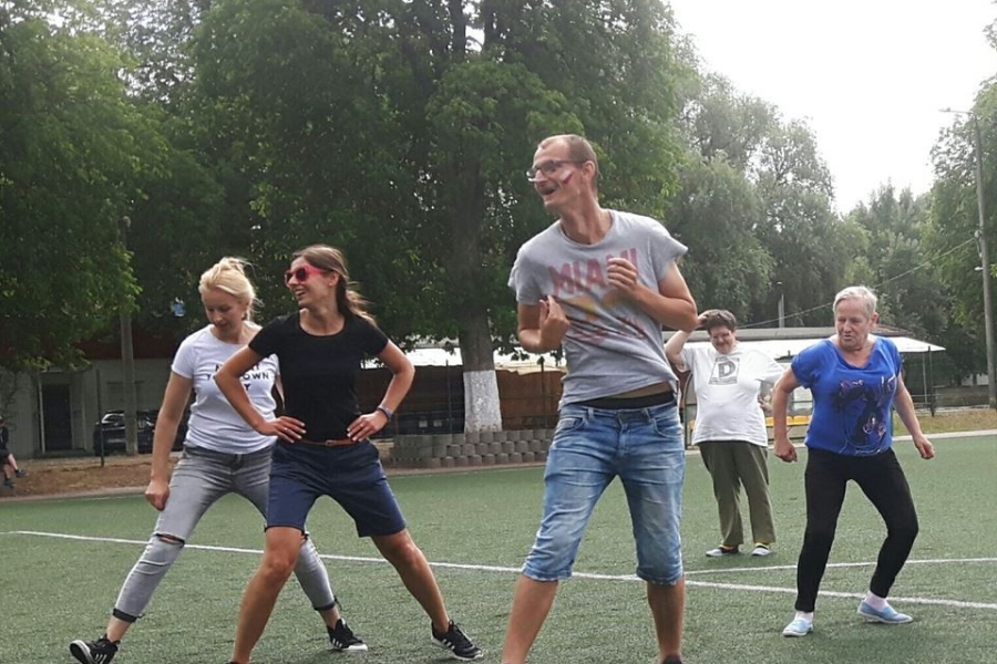 Grupa uczestników stojących w rozkroku na boisku