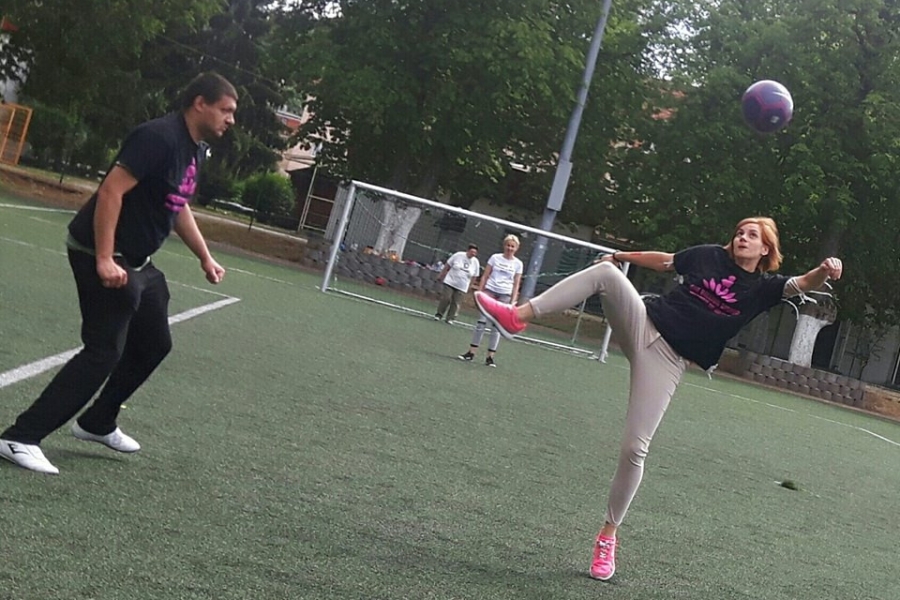 Terapeutka podbijająca piłkę do góry na tle bramki