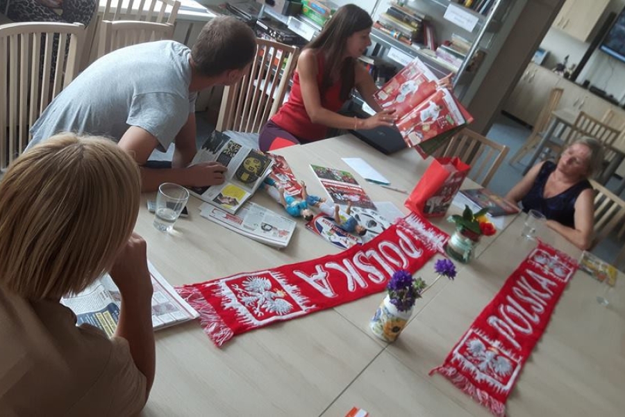 Terapeutka wraz z uczestnikami przeglądająca prasę sportową przy stole