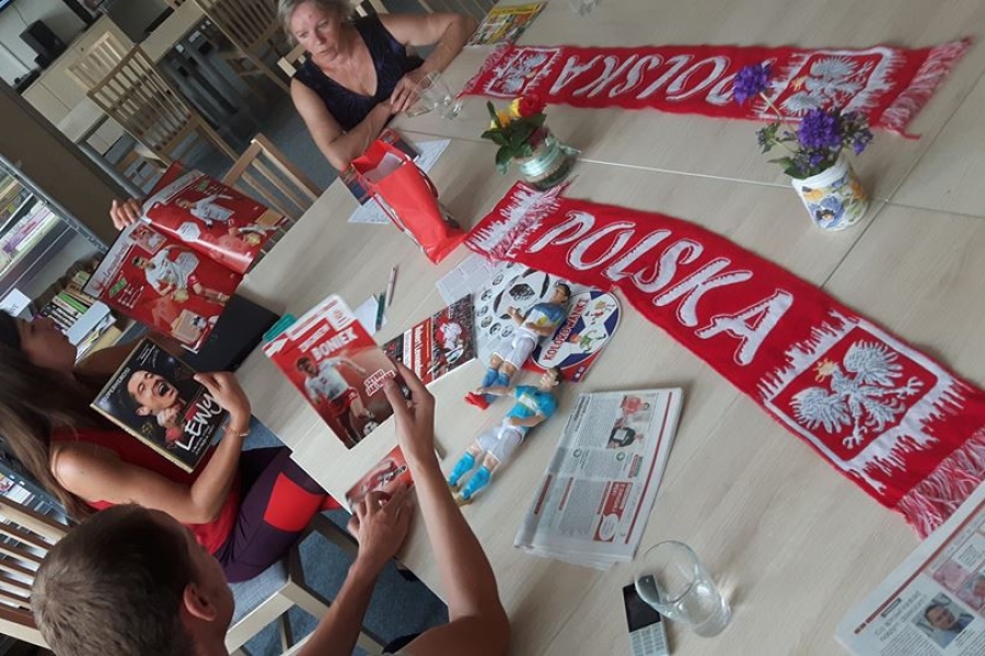 Uczestnicy wraz z terapeutką przeglądają prasę sportową