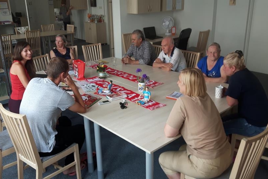 Terapeuci wraz z uczestnikami siedzący przy stole z gadżetami sportowymi